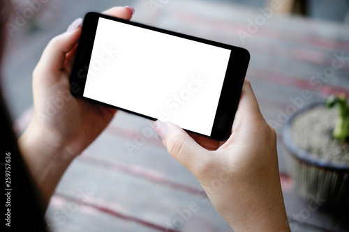 Mock up smartphone of hand holding black mobile phone with blank white screen	