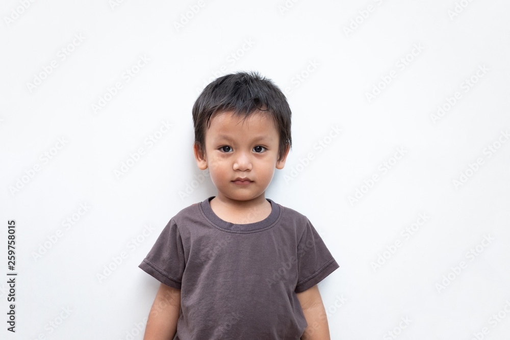 Portrait of a toddler boy wearing grey T-shirt with a little smile on white background