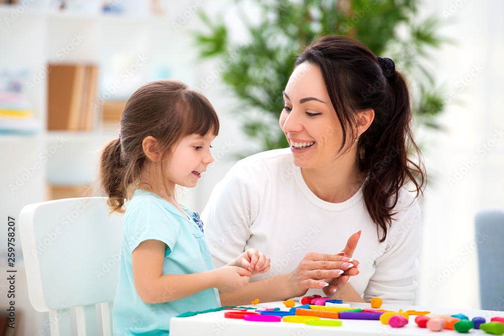 Smiling mother helps a little daughter to sculpt figurines from plasticine. Children's creativity. Happy family Smiling mother helps a little daughter to sculpt figurines from plasticine. Children's creativity. Happy family