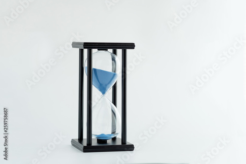 Hourglass with blue sand running through the glass bulbs ; time passing concept