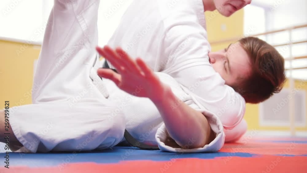 Two athletic men training their aikido skills in the studio. Throwing the opponent on the floor Two athletic men training their aikido skills in the studio. Throwing the opponent on the floor