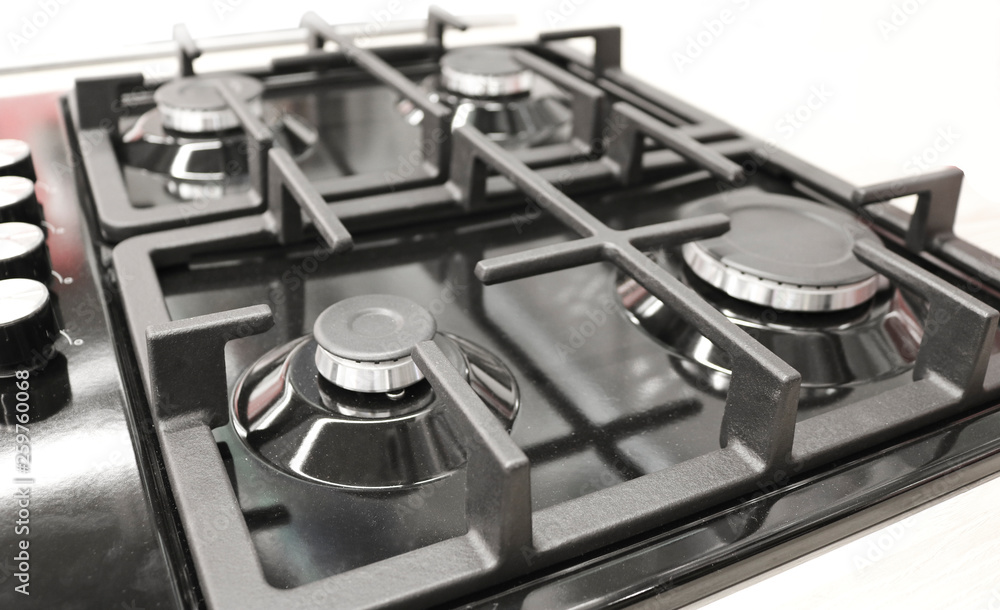 New modern gas stove with four burners for the kitchen, black enamelled surface, cast iron grilles New modern gas stove with four burners for the kitchen, black enamelled surface, cast iron grilles