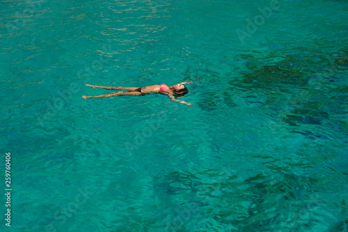 mujer joven flotando en el mar en bikini