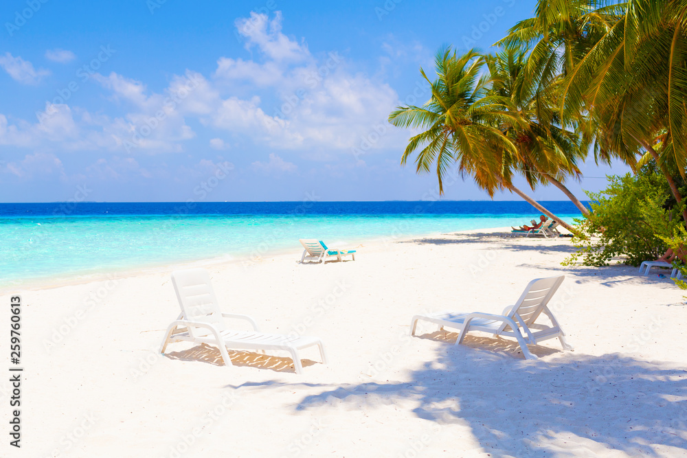 Vacation holidays summer background wallpaper - beach loungers with resting sunbathing reading people in sunny tropical Caribbean beach with white sand at island near the ocean sea with sunbeds