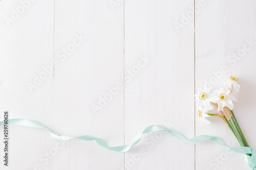 Flat lay composition with white daffodils on a white wooden table