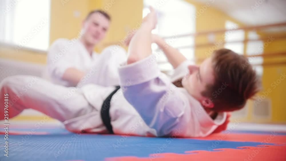 Martial arts. Two athletic men training their aikido skills in the studio. Lying on the floor Martial arts. Two athletic men training their aikido skills in the studio. Lying on the floor