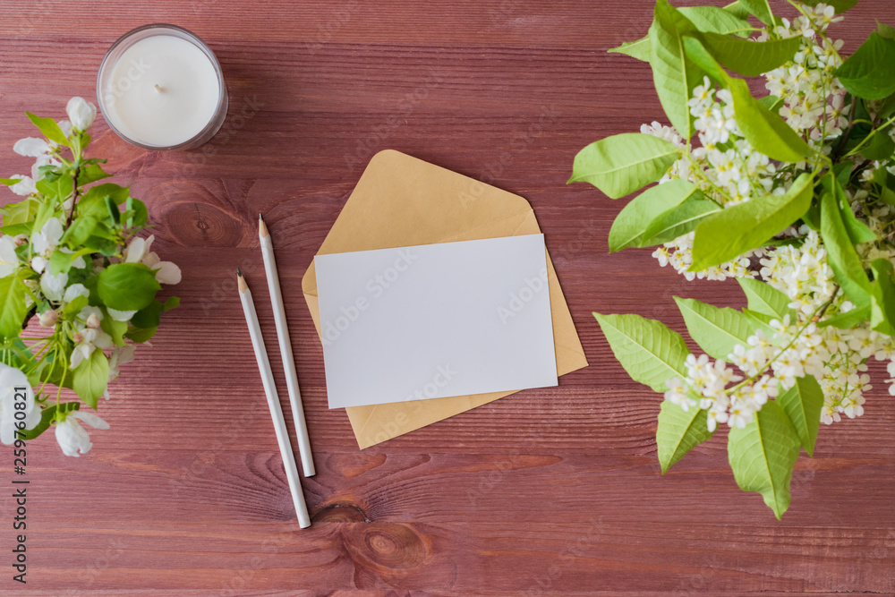 Mockup white greeting card and envelope with spring white flowers on a wooden background