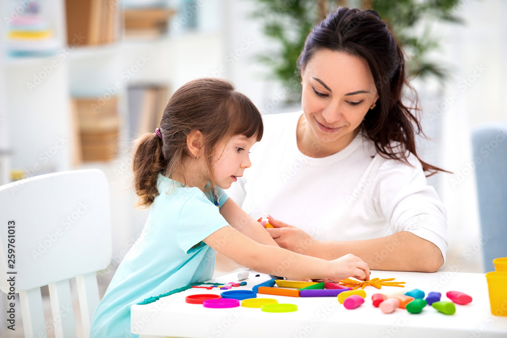 Smiling mother helps a little daughter to sculpt figurines from plasticine. Children's creativity. Happy family Smiling mother helps a little daughter to sculpt figurines from plasticine. Children's creativity. Happy family