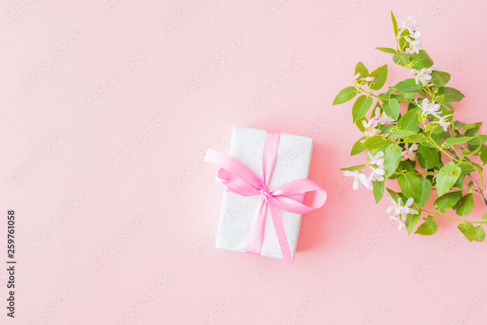 Flat lay composition with branches and green leaves and gift box on a pink background Flat lay composition with branches and green leaves and gift box on a pink background