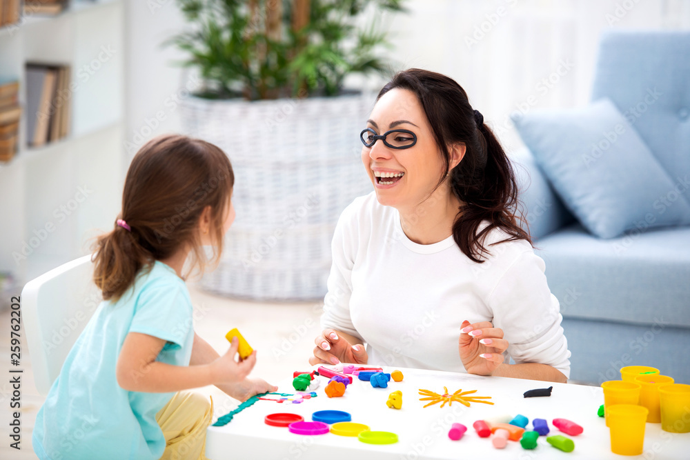 Fototapeta premium How to save healthy eyesight. Mom and daughter make glasses from plasticine