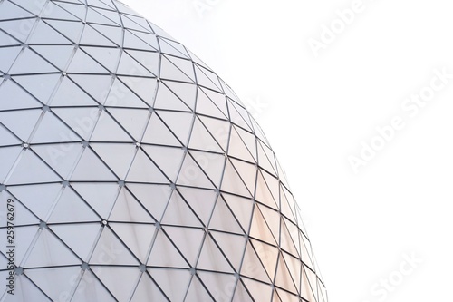 A glass surface of a triangle pattern outside a high modern building in the city on white sky background 