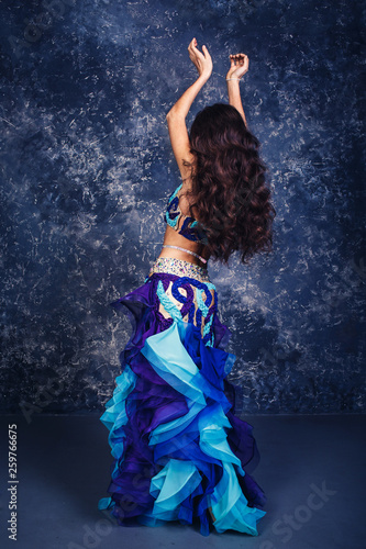 Young attractive girl in a blue suit dancing belly dance.