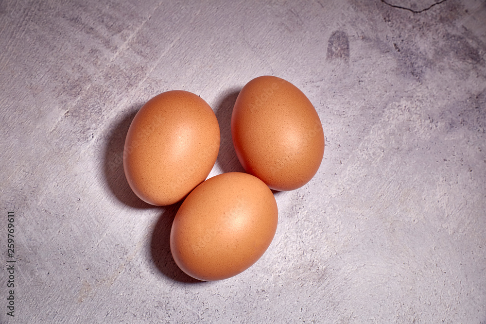 three orange eggs of farm chicken on a cement background three orange eggs of farm chicken on a cement background