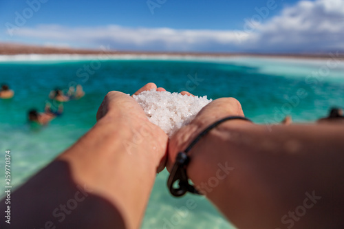 View of hand full of salt in with the laguna escondida in the background in the San Pedro de Atacama deserrt photo