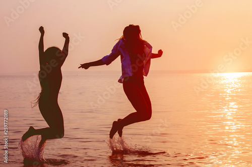 Two girls having fun in the sea at sunset.