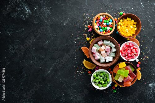 Colorful candies and lollipops. On a black stone background. Top view. free copying space.