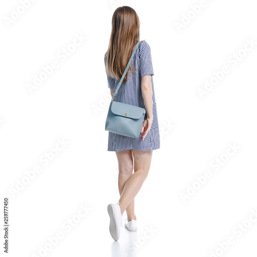 Woman in blue dress with bag looking walking goes on white background isolation, back view