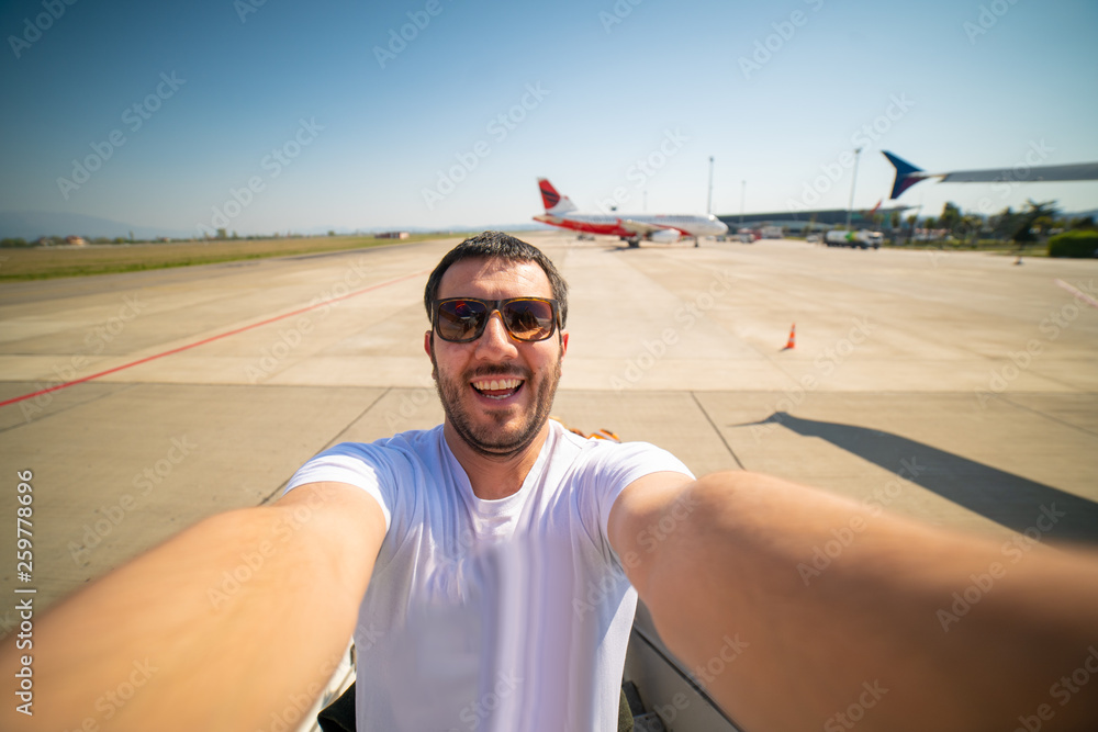 alone man taking selfie in the airport before flight with airplane