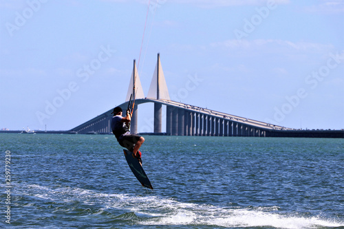 Kite surfer gaining air with a kite above as he attempts to jump the skyway bridge