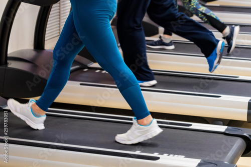 Close up legs of people on modern treadmills in gym. Lower part view