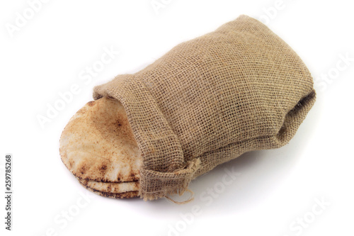 Pita bread isolated on white background of rustic fabric bag. Food of Arab cuisine
