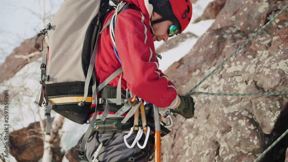 Climber glasses and a helmet with a beard winds up the rope by which he descended down a steep slope Climber glasses and a helmet with a beard winds up the rope by which he descended down a steep slope