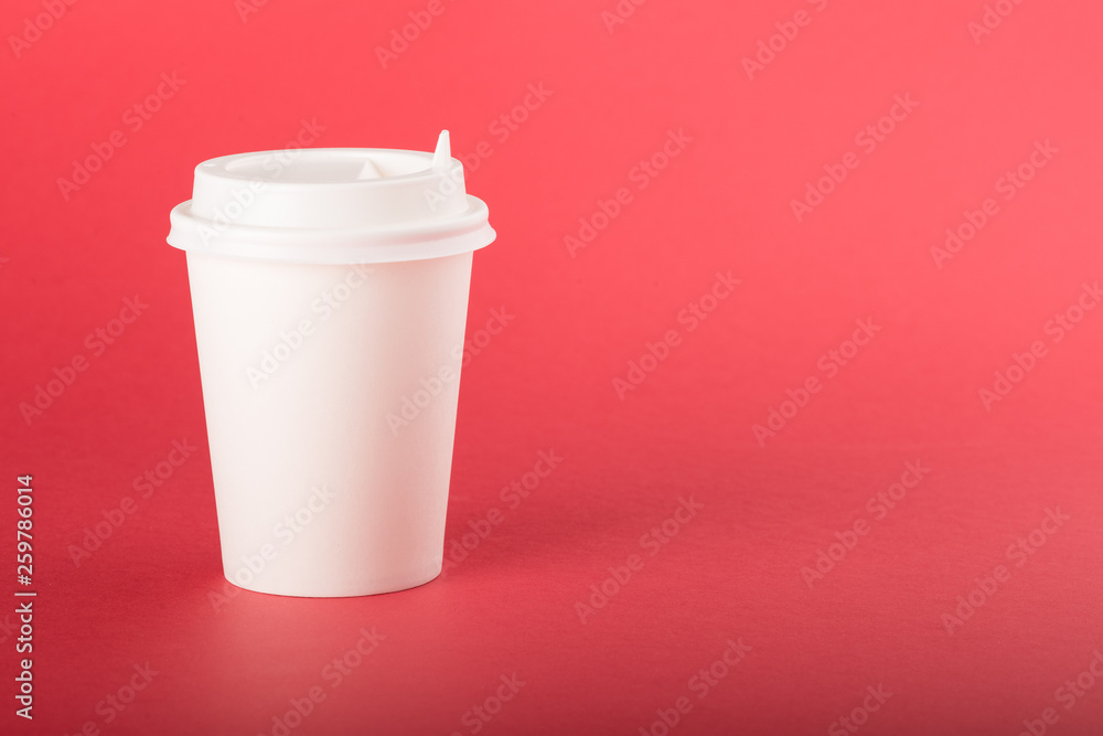 White disposable paper cup with white cap on a red background White disposable paper cup with white cap on a red background