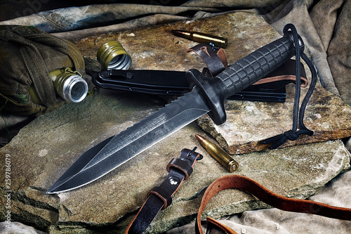 combat knife, flask and ammunition on the stone