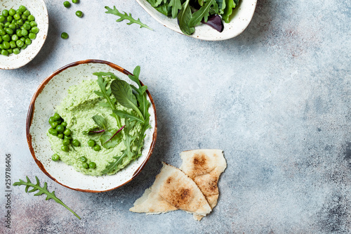 Green pea hummus spread or dip with mix salad leaves. Healthy raw summer appetizer, vegan, vegetarian snack. Copy space