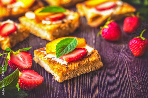 crunchy croutons with soft cheese and fresh strawberries. lunch of berry sandwiches. sandwiches with strawberries and mint leaves close-up.