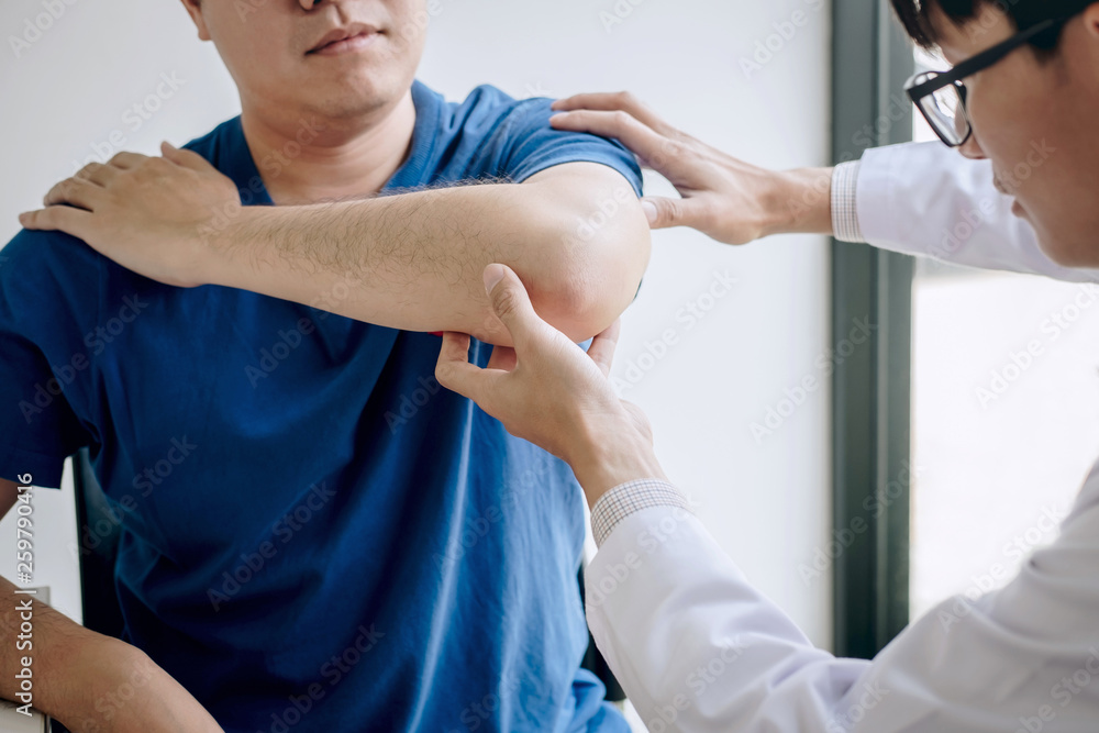 Obraz premium Doctor physiotherapist assisting a male patient while giving exercising treatment massaging the arm of patient in a physio room, rehabilitation physiotherapy concept