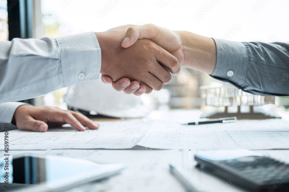 Handshake of collaboration, Construction engineering or architect discuss a blueprint and building model while checking information on sketching, meeting for architectural project of partner