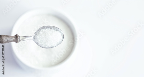 crystal sugar in a spoon on the background of a bowl of sugar close-up. background with sugar. the concept of sweet tooth in the form of sugar in a spoon.