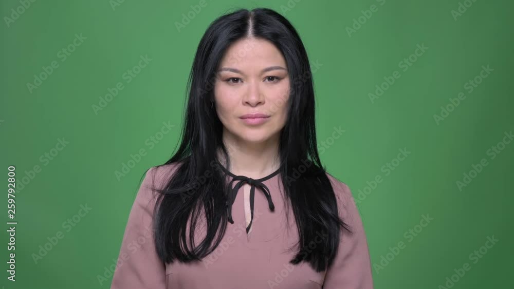 Closeup shoot of young attractive asian female with black hair showing a thumb up and smiling Closeup shoot of young attractive asian female with black hair showing a thumb up and smiling