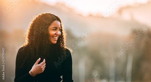 Happy attractive young African American lady looking away on blurred background