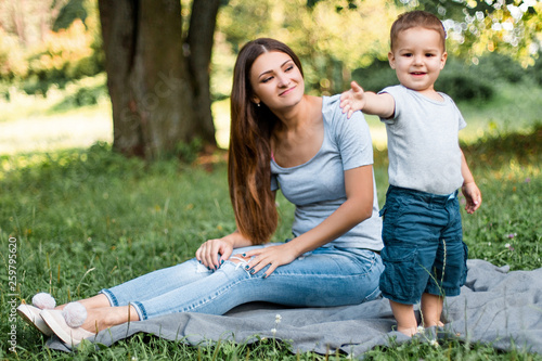 Mother with little son spend time together in green park.