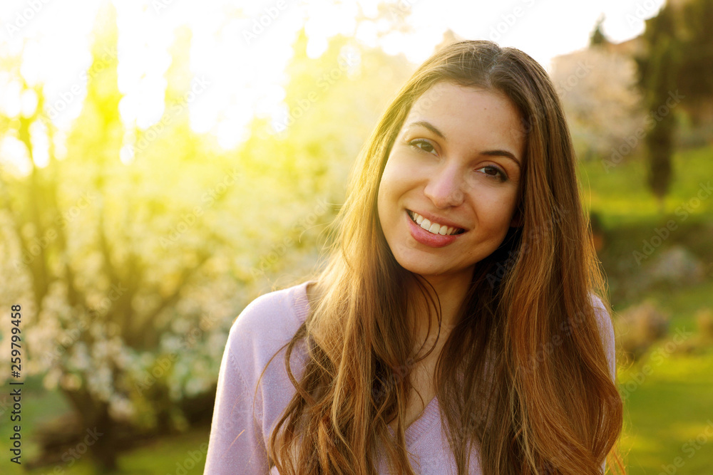 Woman smiling with perfect smile in park at spring time Sunlight flare. Woman smiling with perfect smile in park at spring time Sunlight flare.