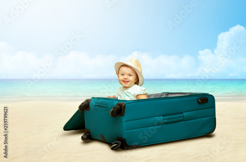 Baby girl sitting in suitcase on the beach.