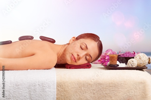 Young woman in spa salon, getting stones massage