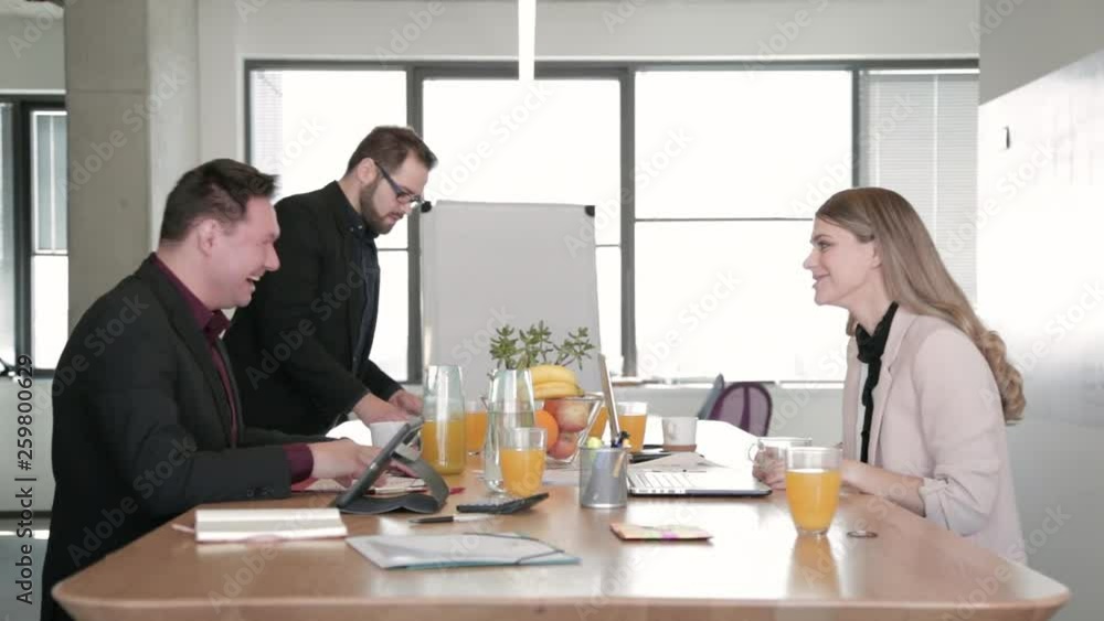 Static shot of two young business people sitting at the office desk, exchanging ideas, having fun, laughing and drinking coffee during a meeting. Static shot of two young business people sitting at the office desk, exchanging ideas, having fun, laughing and drinking coffee during a meeting.