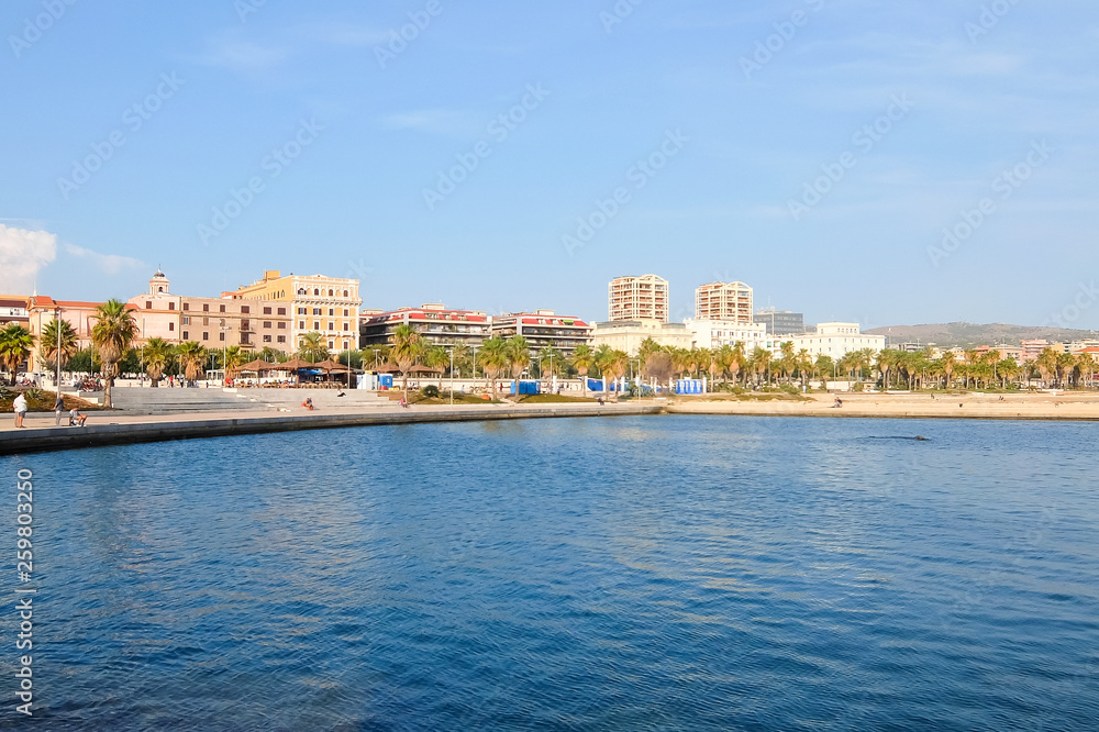 Civitavecchia, Italy. View View of the embankment of Civitavecchia with green palm trees, blue sky, old typical roman houses and promenade along the coast in Lazio, Italy.