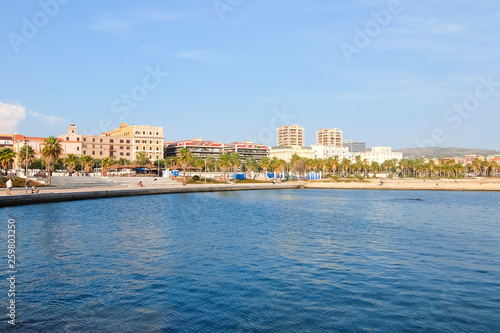 Civitavecchia, Italy. View View of the embankment of Civitavecchia with green palm trees, blue sky, old typical roman houses and promenade along the coast in Lazio, Italy. © Denis