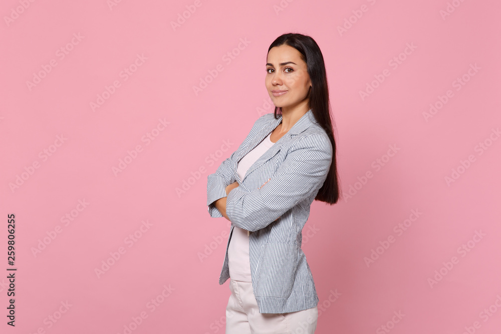 Portrait of attractive smiling young woman in striped jacket holding hands crossed isolated on pink pastel wall background in studio. People sincere emotions, lifestyle concept. Mock up copy space. Portrait of attractive smiling young woman in striped jacket holding hands crossed isolated on pink pastel wall background in studio. People sincere emotions, lifestyle concept. Mock up copy space.