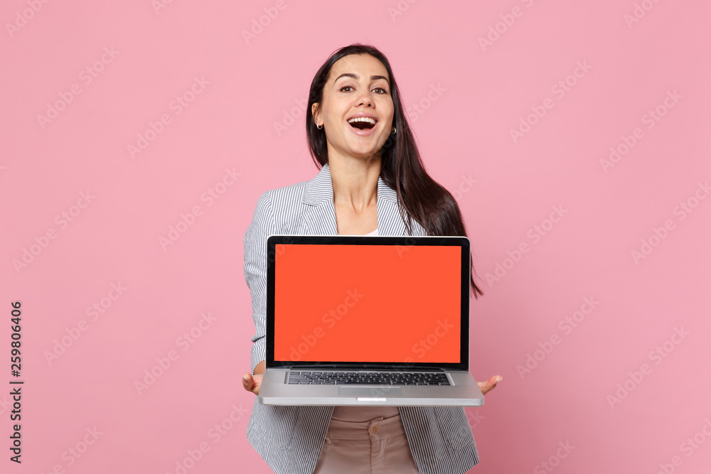 Portrait of laughing young woman in striped jacket holding laptop pc computer with blank empty screen isolated on pink pastel background. People sincere emotions lifestyle concept. Mock up copy space. Portrait of laughing young woman in striped jacket holding laptop pc computer with blank empty screen isolated on pink pastel background. People sincere emotions lifestyle concept. Mock up copy space.