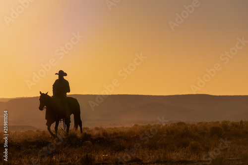 Lone Desert Cowboy Riding At Sunrise