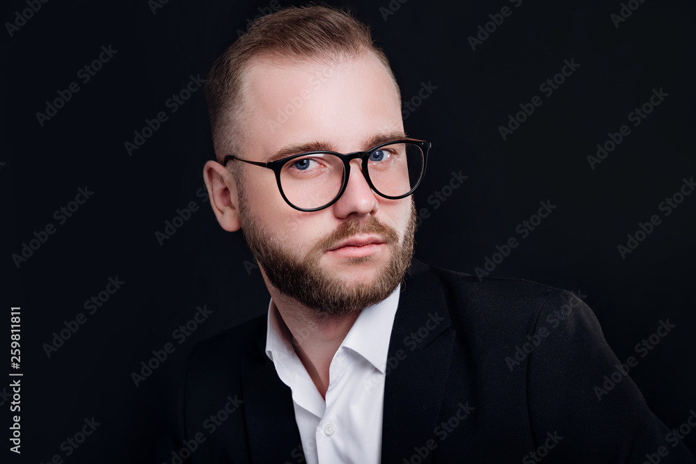 Stylish handsome bearded man with glasses in trendy suit on black background Stylish handsome bearded man with glasses in trendy suit on black background