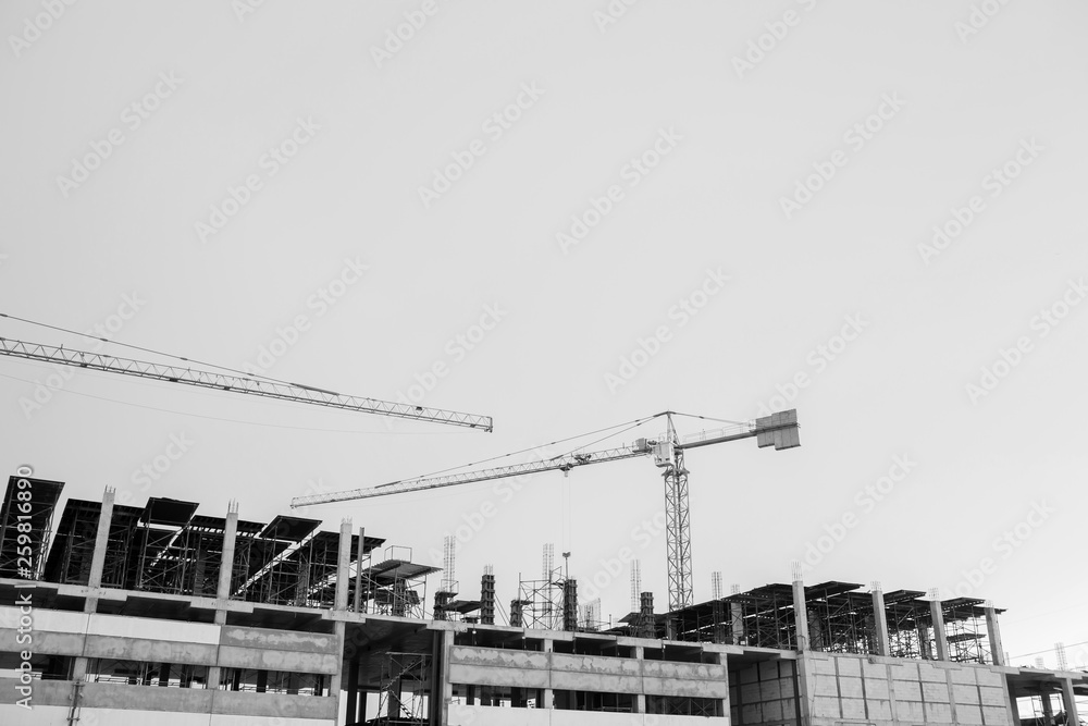 black and white image of building crane and buildings under construction.