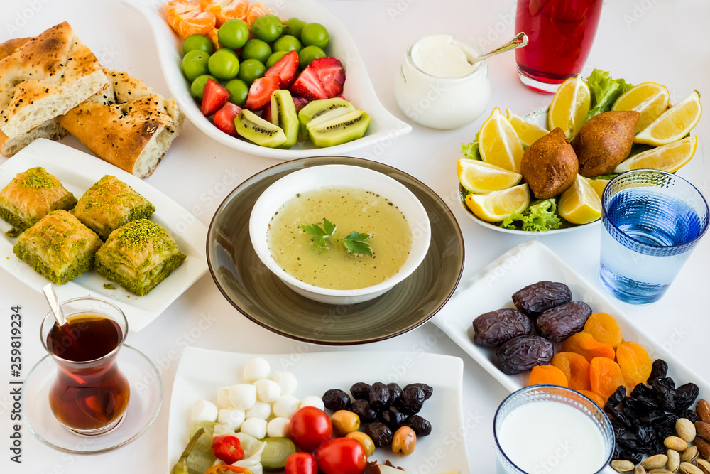 Traditional Ramadan Dinner,iftar  table with soup,baklava,pide,stuffed meatball,dry date fruits, Turkish Tea,fresh fruits and black olives designed around of soup.