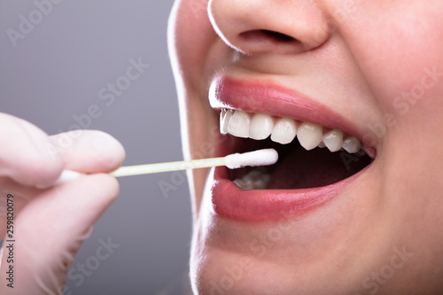 Dentist's Hand Taking Saliva Test From Woman's Mouth