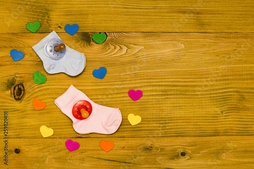  Baby supplies for boy and girl and heart shapes on wooden table.Baby announcement concept.Toned photo.